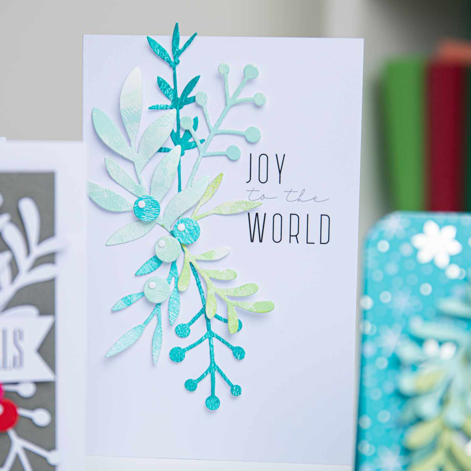 Thinlits Die Set Buds & Branches: Karte mit blauen und grünen Zweigen, Text "Joy to the World", Sizzix.