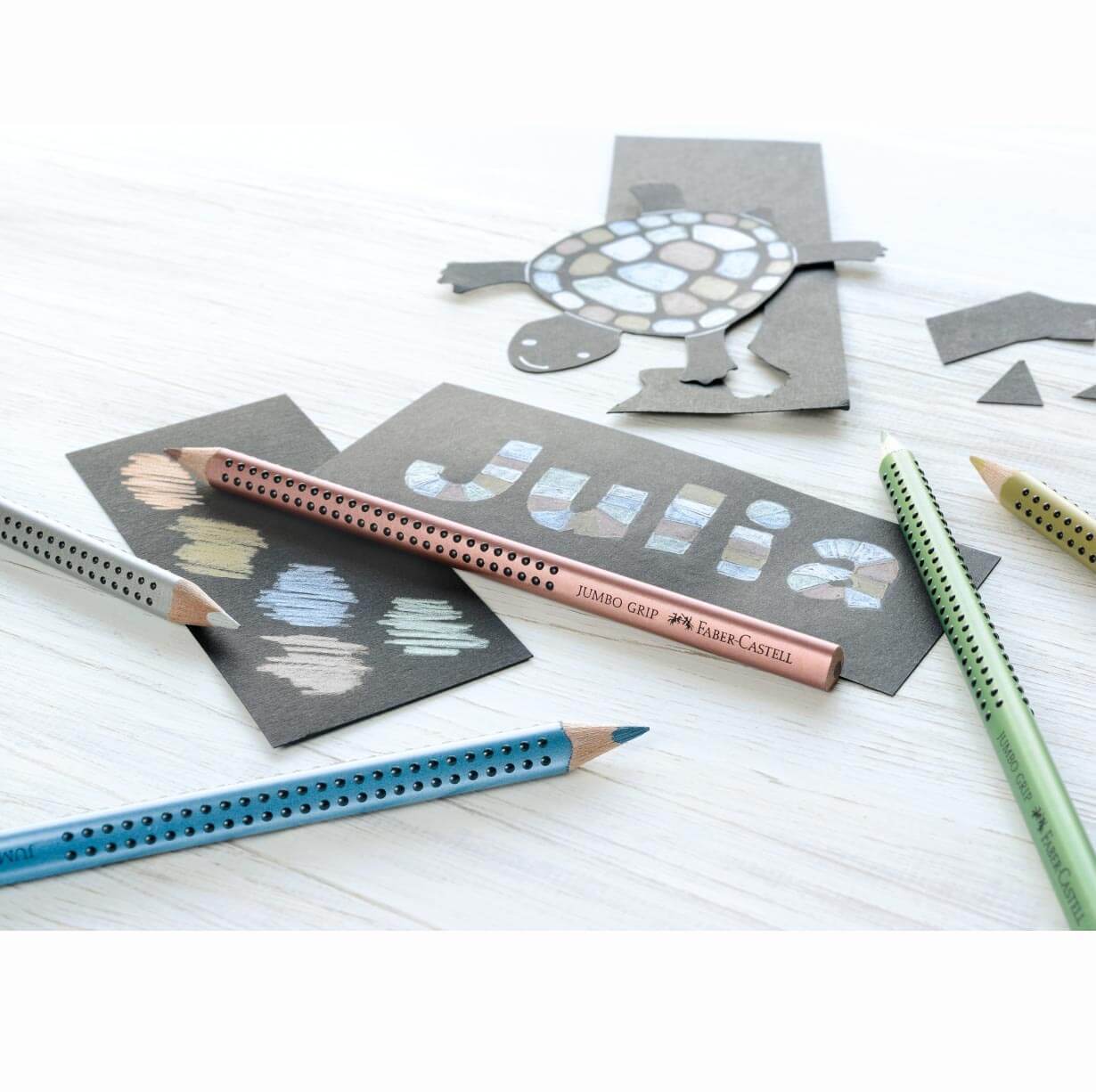Jumbo Grip metallic Buntstifte von Faber Castell in Grün, Blau und Kupfer auf weißem Tisch.