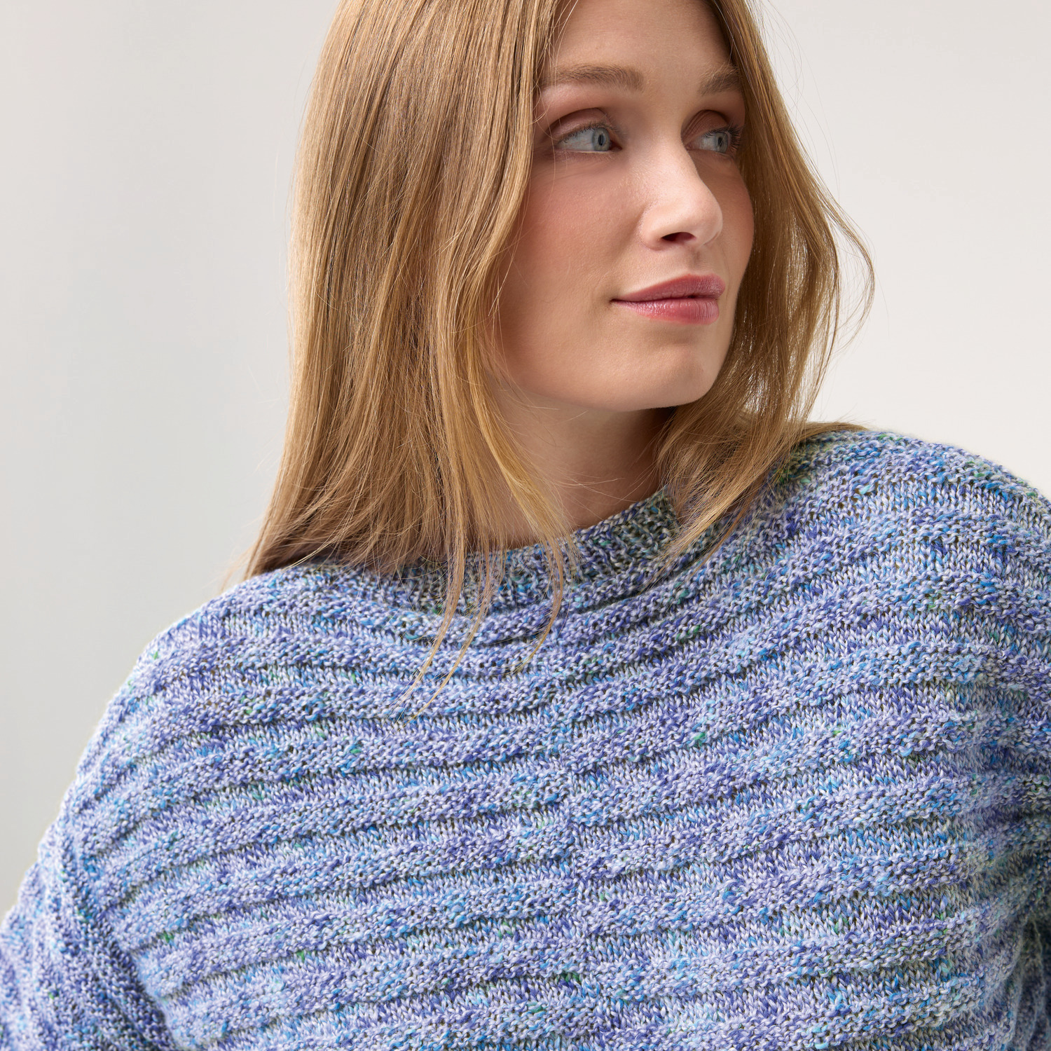Strickset Shirt Modell 25 aus Die Neue Masche Nr. 9, in Blau- und Lilatönen, getragen von einer Frau mit langen Haaren.