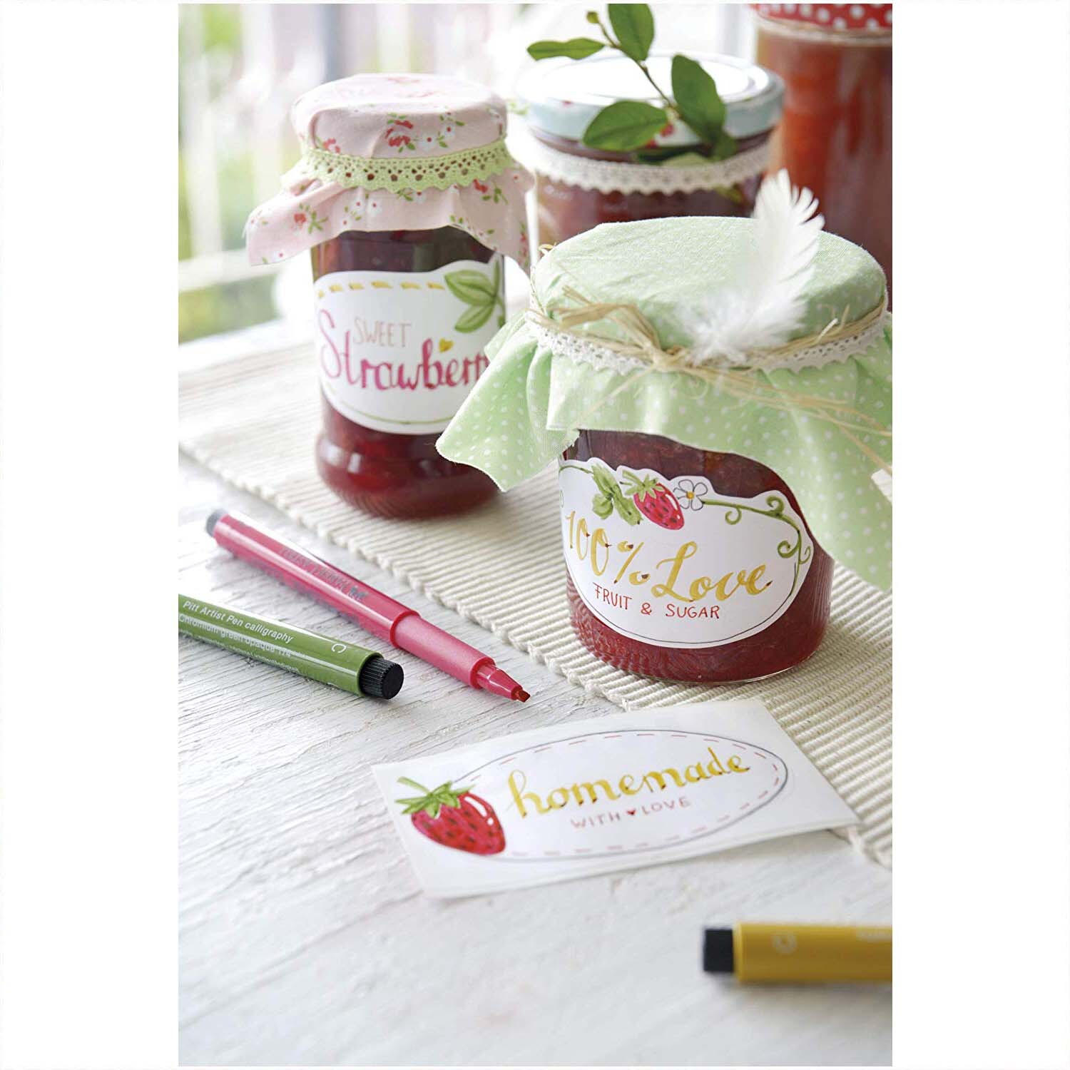 Tuschestift Pitt Artist Pen Calligraphy 8 Stück von Faber Castell neben Marmeladengläsern auf einem Tisch.