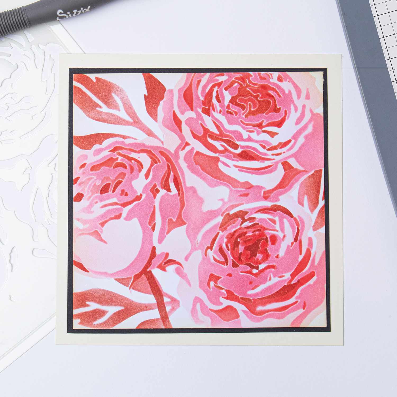 Layered Stencils Layered Peony zeigt ein lebendiges Blumenmuster in Rosa- und Rottönen von Sizzix. Ideal für kreative Bastelprojekte.