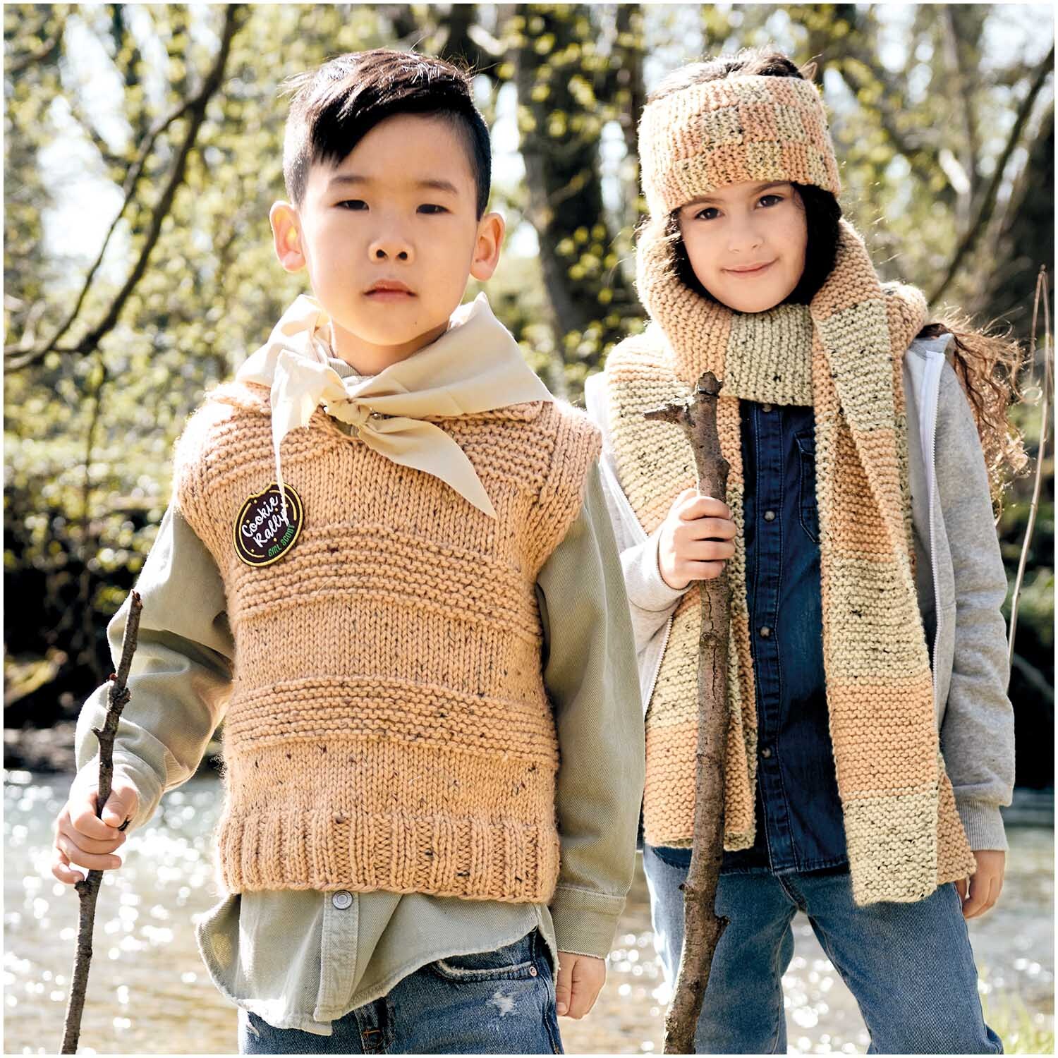 Essentials Mega Wool Tweed chunky: Zwei Kinder in gestrickter Kleidung aus Apricot-Wolle von Rico Design, im Freien mit Stöcken.