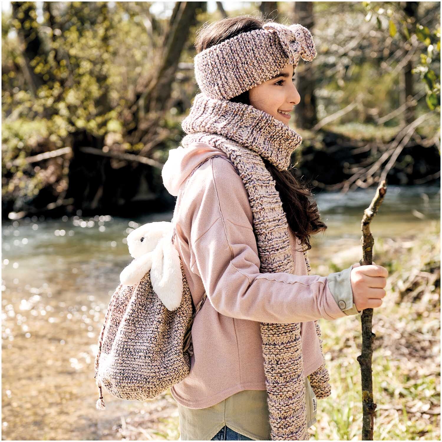 Creative Make it Glitter: Frau mit gestricktem Stirnband und Schal in Natur, nahe einem Flussufer.