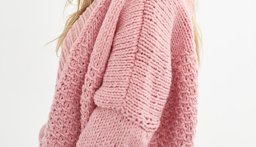 Strickanleitung Jacke aus Polar: Nahaufnahme einer rosa gestrickten Jacke mit detailliertem Muster.
