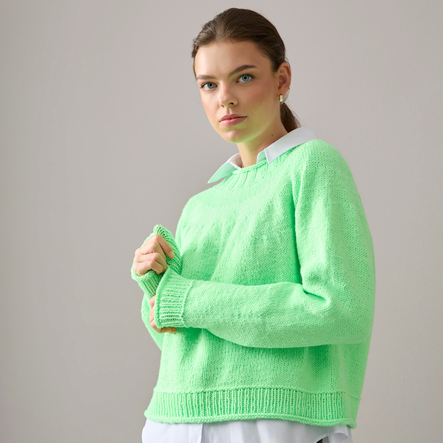 Vegan Cashmere Special: Grüner Pullover aus veganem Kaschmir, getragen von Frau vor grauem Hintergrund.