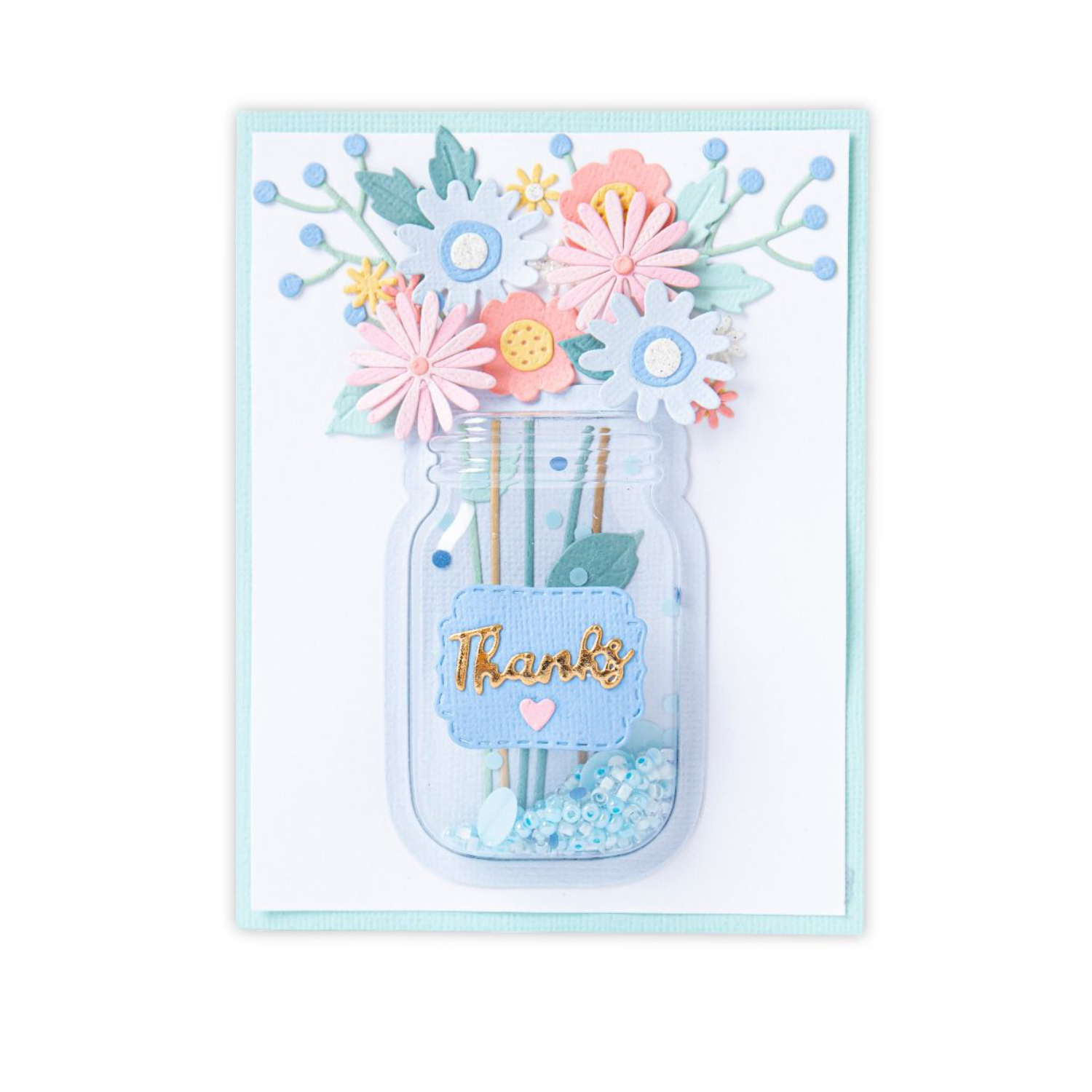 Sizzix "Making Essential Shaker Domes 6PK" in Pastellfarben zeigt ein Glas mit Blumen und dem Wort "Thanks". Ideal für kreative Bastelprojekte und Grußkarten.
