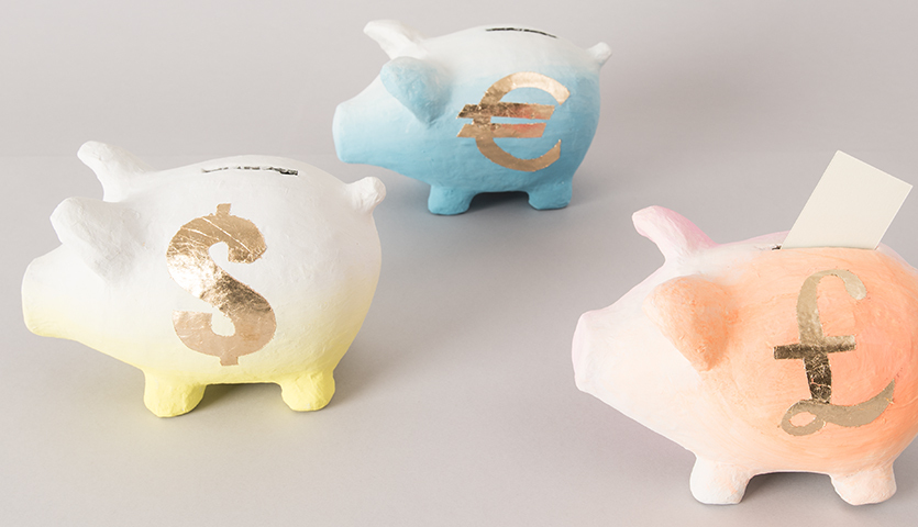 Anleitung Sparschwein gestalten: Drei bunte Sparschweine mit goldenen Währungssymbolen auf grauem Hintergrund.