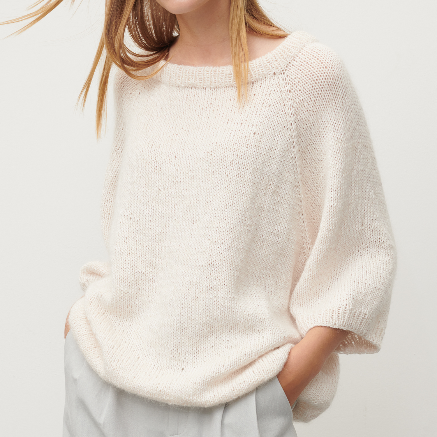 Strickanleitung sportliches Shirt: Frau trägt ein lässiges, cremefarbenes Strickshirt mit kurzen Ärmeln.