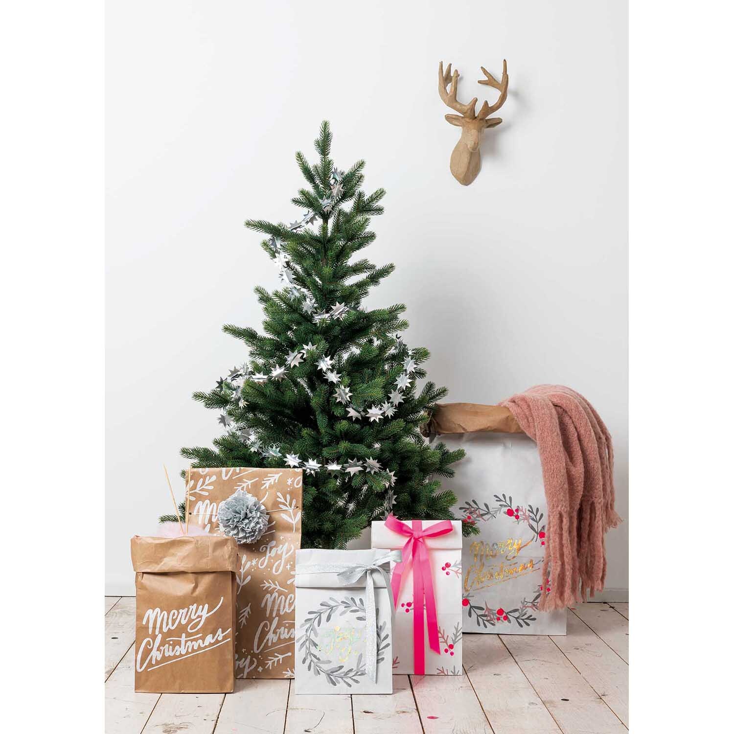 Paper Poetry Metallicband dekoriert Geschenke unter einem Weihnachtsbaum mit Hirschkopf-Dekoration.