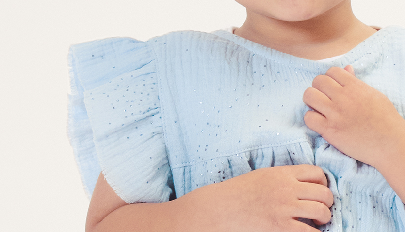 Nähanleitung Kinderkleid aus Krinkelmusselin: Ein Kind trägt ein hellblaues Kleid mit Rüschenärmeln.