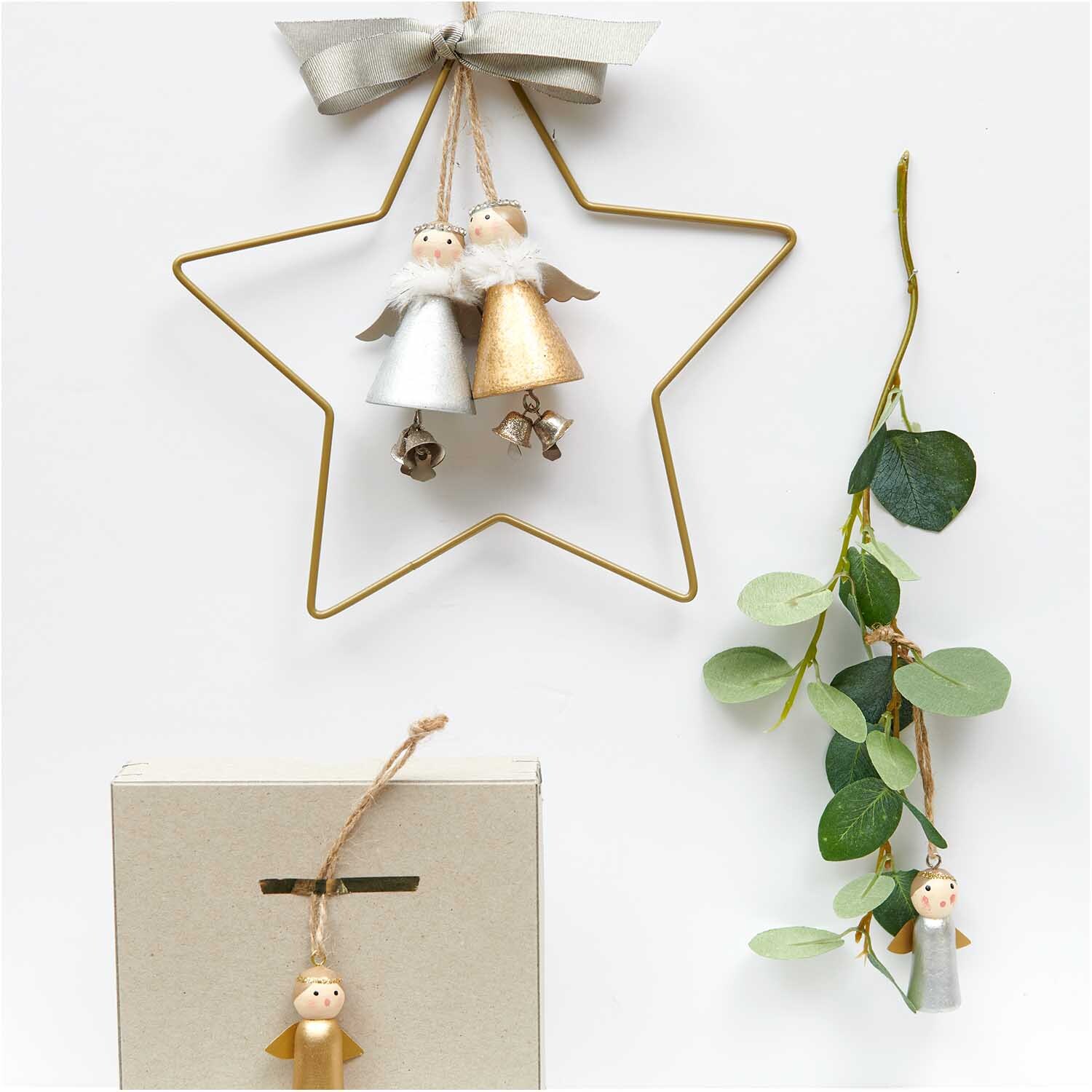 Holzhänger Engel mit Glöckchen silber 8cm von Rico Design, dekoriert an einem goldenen Stern mit Eukalyptuszweig.