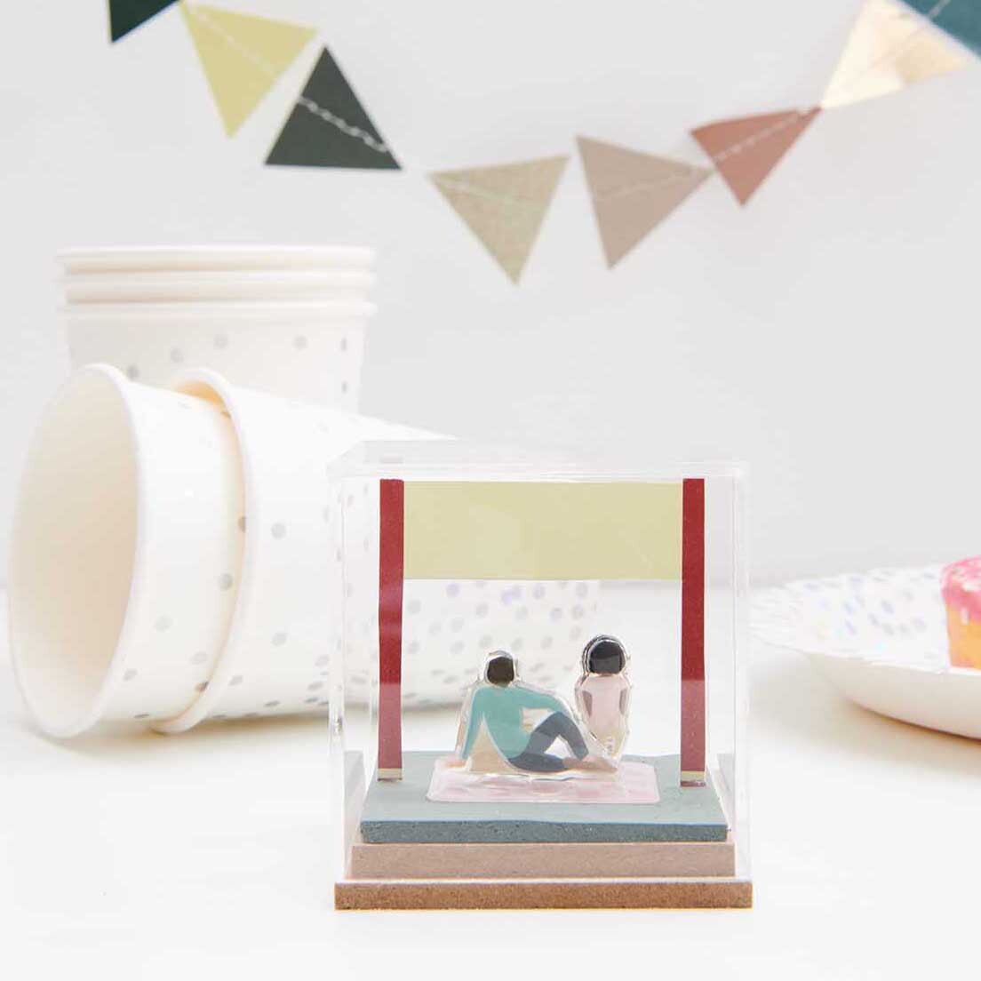 Figurico Gelsticker Park: Miniatur-Szene in Acrylbox, umgeben von pastellfarbenen Partydekorationen.