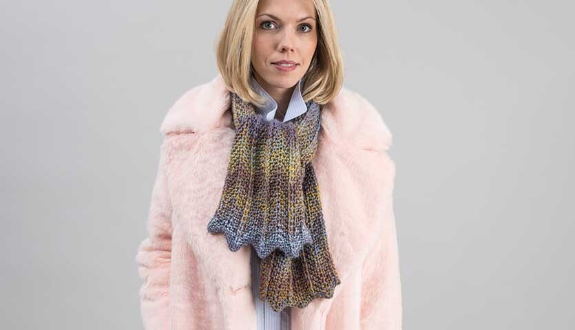 Strickanleitung Schal aus Creative Ito Iro chunky: Frau trägt bunten Schal und rosa Mantel.