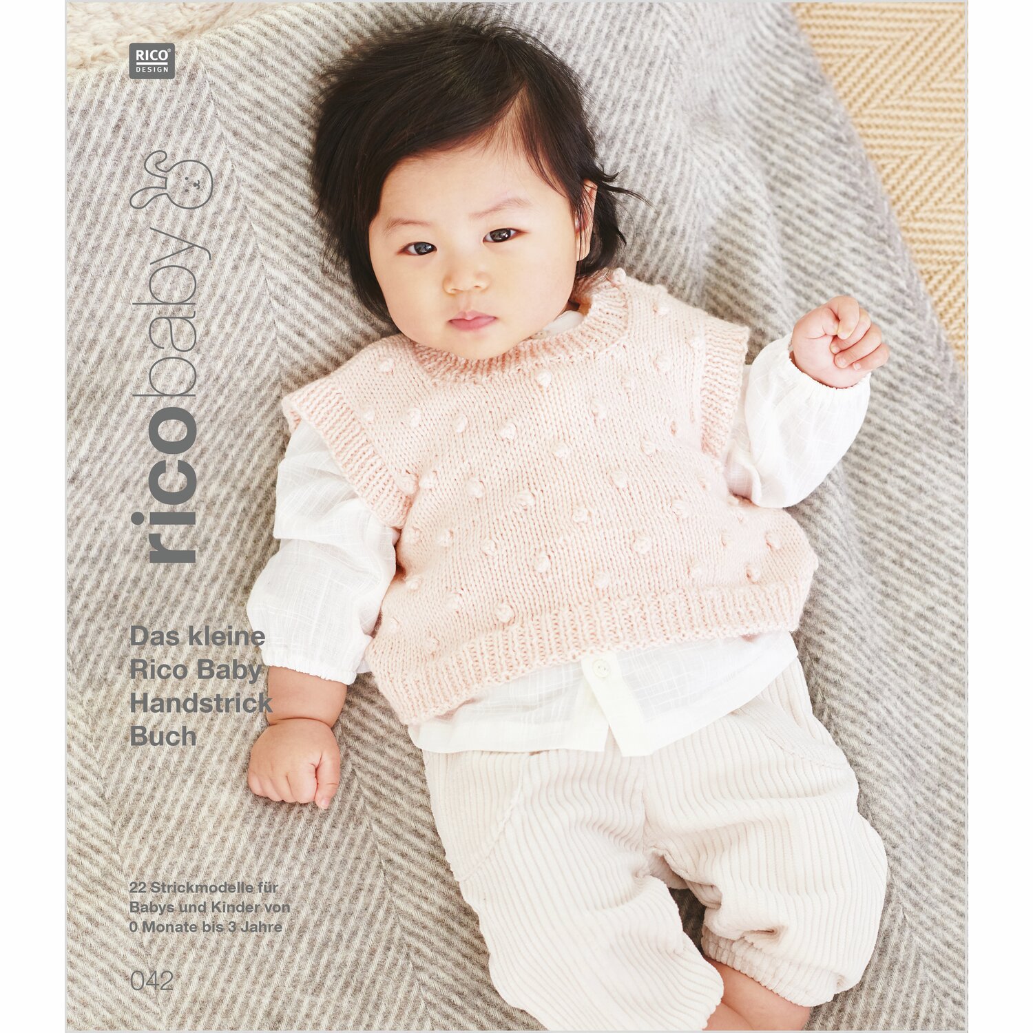 Rico Baby 042: Baby in cremefarbenem Strickset von Rico Design, liegend auf grauer Decke.