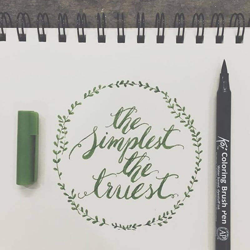 Coloring Brush Pen von Koi neben einem Blatt mit kalligrafischem Text und grünem Stiftdeckel. Ideal für kreative Designs.