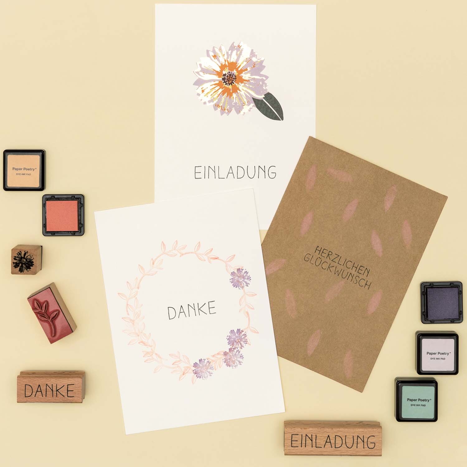 Anleitung Grußkarten mit floralen Motiven gestalten: Drei Karten mit Blumenmotiven und Stempeln auf beigem Hintergrund.
