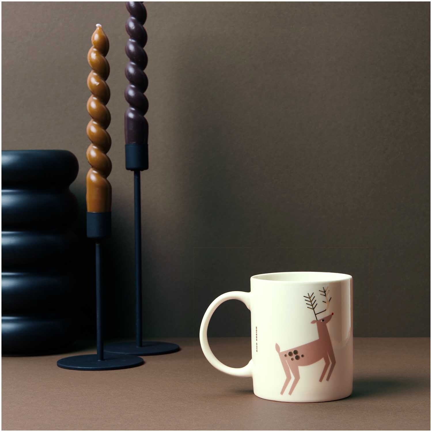 Porzellan Tasse Rentier 8x9,5cm von Rico Design neben dekorativen, gedrehten Kerzen.