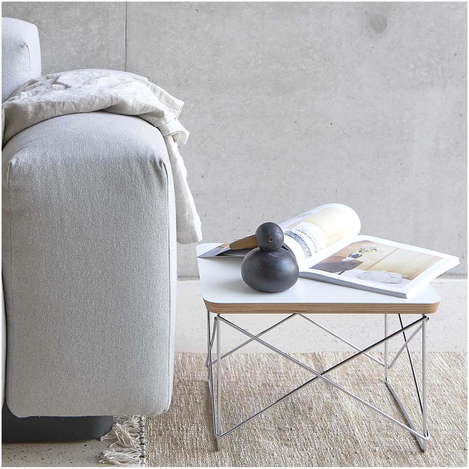 Möwe sitzend Holz schwarz 10x10,5cm auf modernem Beistelltisch neben grauem Sofa und Magazinen.