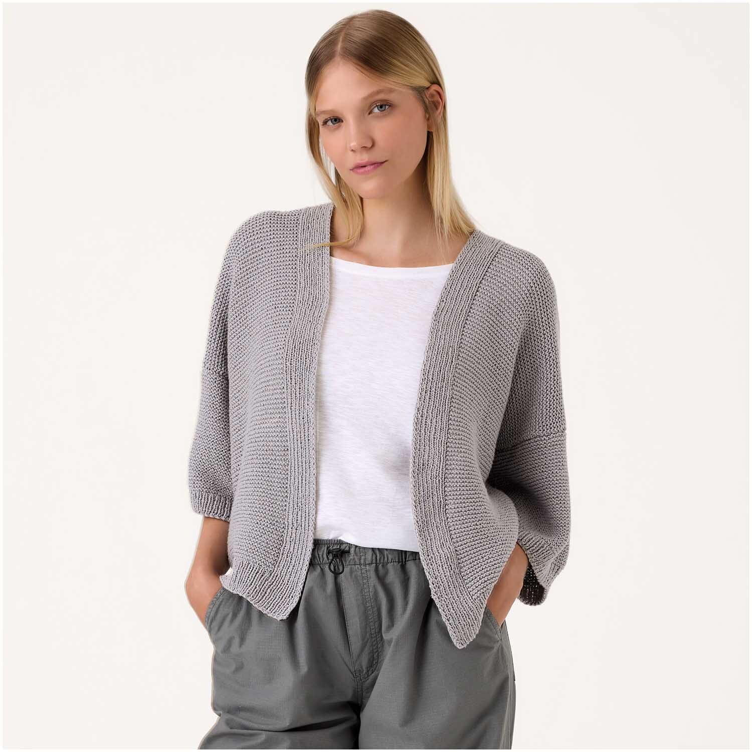 Luxury Organic Cotton Silk dk: Frau trägt grauen Strickcardigan von Rico Design, kombiniert mit weißem Shirt und grauer Hose.