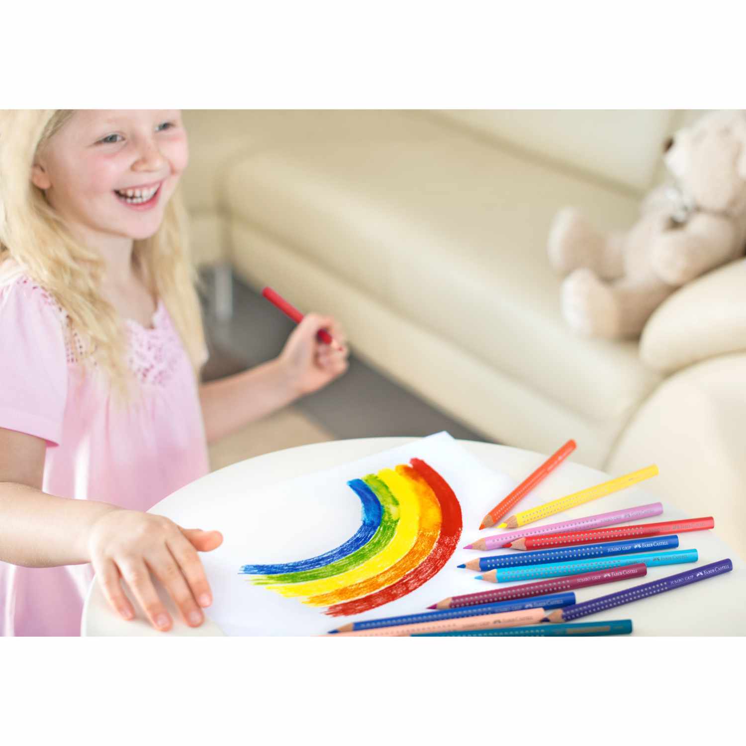 Jumbo Grip Farbstift 12er-Kartonetui: Ein Kind malt mit bunten Stiften von Faber Castell auf einem Tisch.