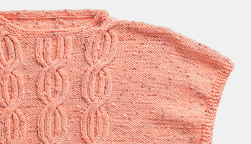 Strickanleitung Zopfmuster-Top aus Fashion Cotton Neps dk: Rosa gestricktes Top mit Zopfmuster auf hellem Hintergrund.