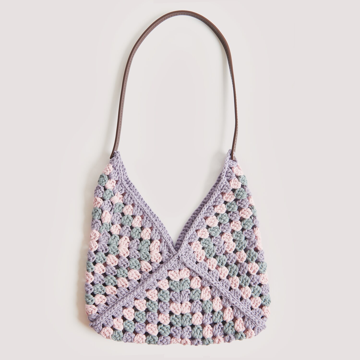 Die Neue Masche No. 12 Frühjahr-Sommer: Handtasche im Granny-Square-Design aus Lavendel- und Grautönen mit braunem Henkel.