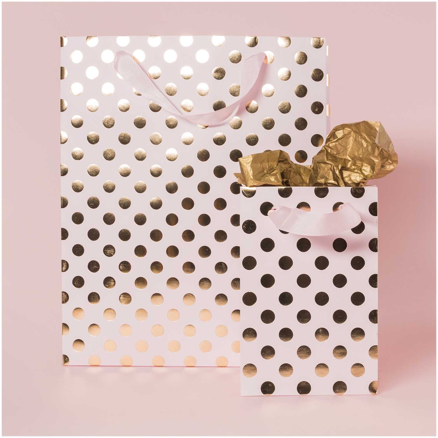 Geschenktüte mit goldenen Punkten auf rosa Hintergrund, ideal für stilvolle Geschenke.