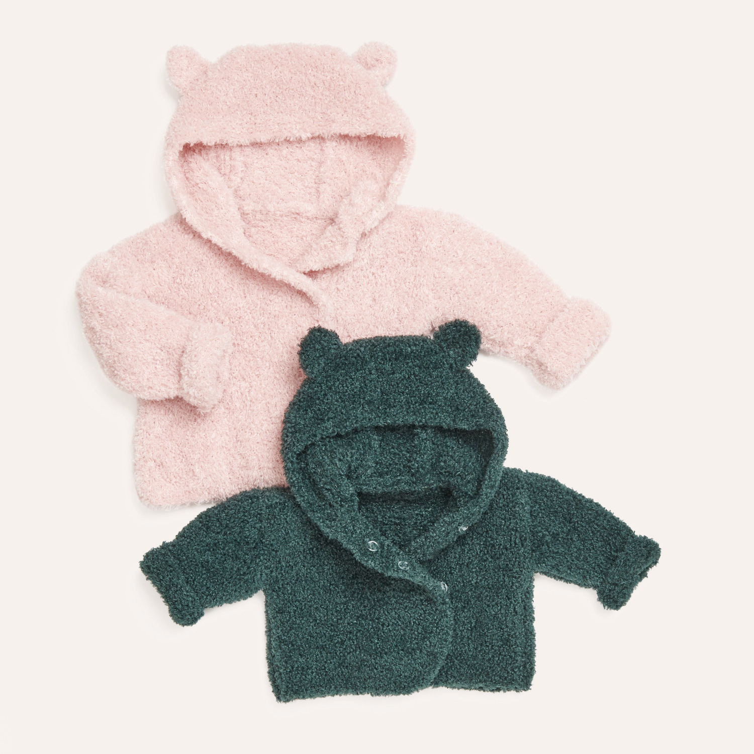 Strickset Jacke Modell 01 aus Rico Baby 040: Zwei flauschige Babyjacken mit Kapuze und Ohren in Rosa und Dunkelgrün.