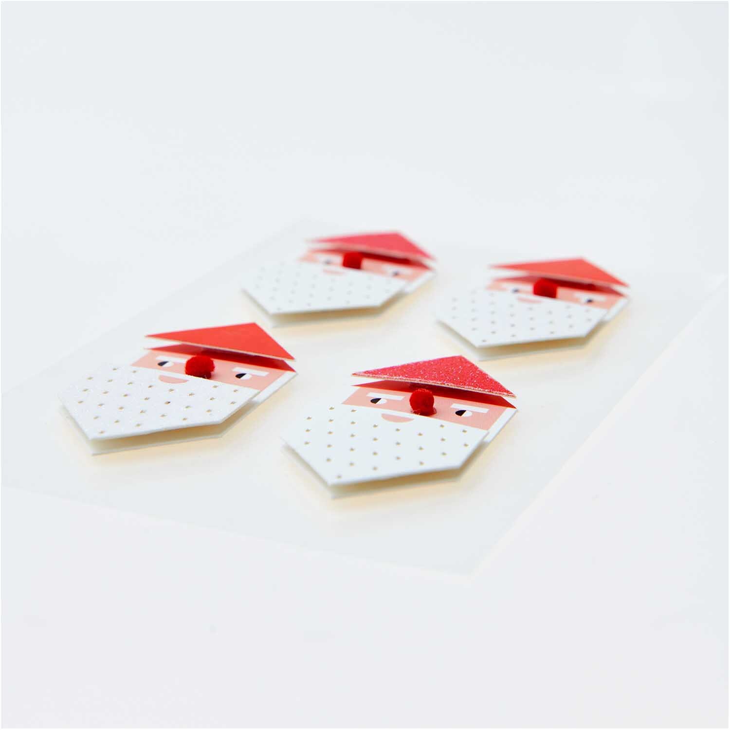 Paper Poetry 3D Sticker Weihnachtsmann zeigt vier stilisierte Weihnachtsmann-Gesichter mit roten Mützen und weißen Bärten.