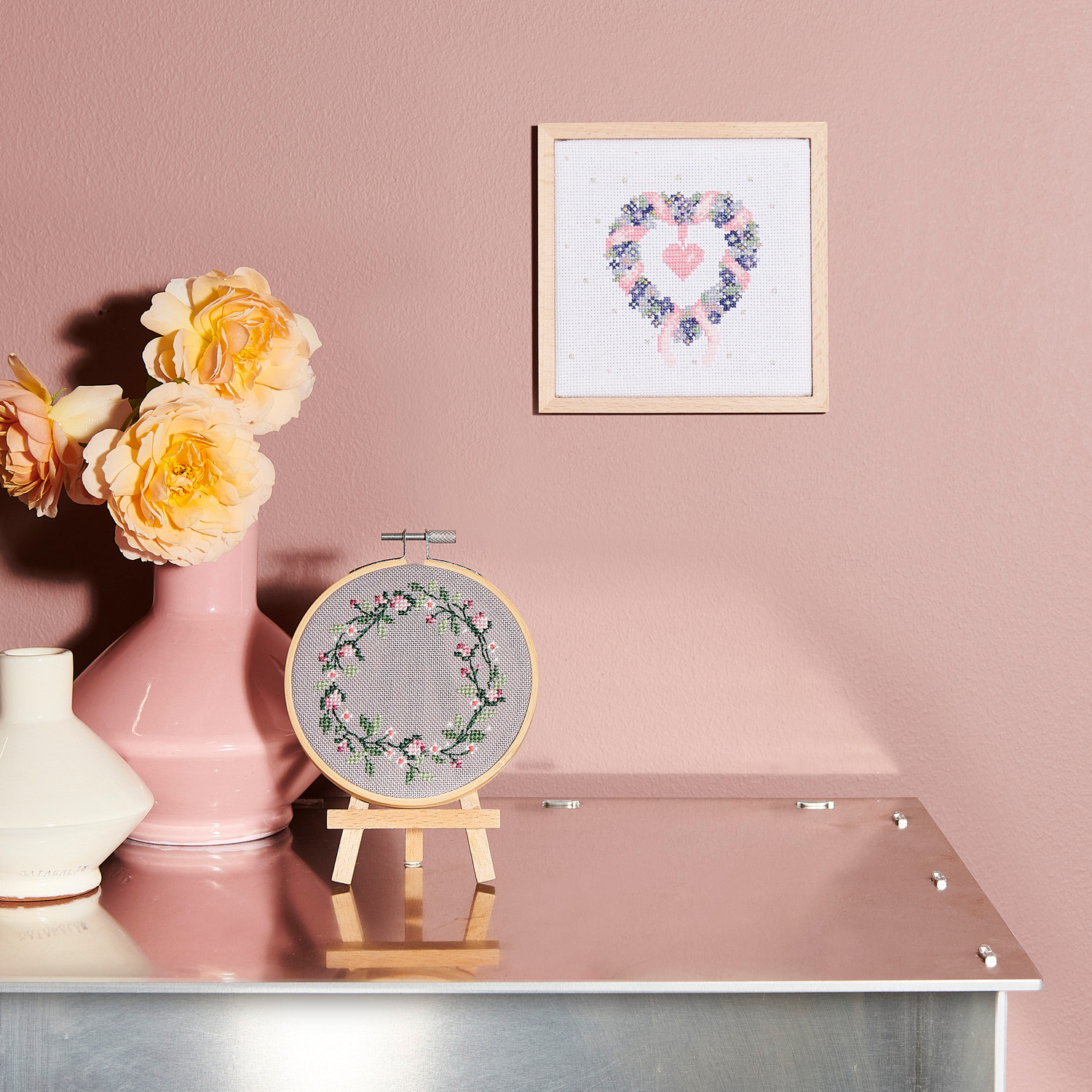 Stickpackung Bild Blumenkranz zeigt einen floralen Kranz in Pastelltönen auf rosa Wand.