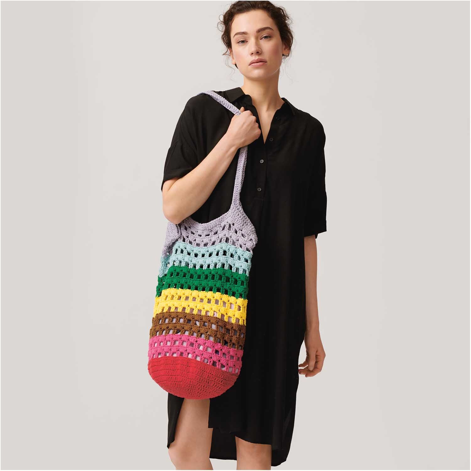 Cotton Universal: Frau in schwarzem Kleid mit bunter, gehäkelter Tasche aus Wolle Rödel in verschiedenen Farben.