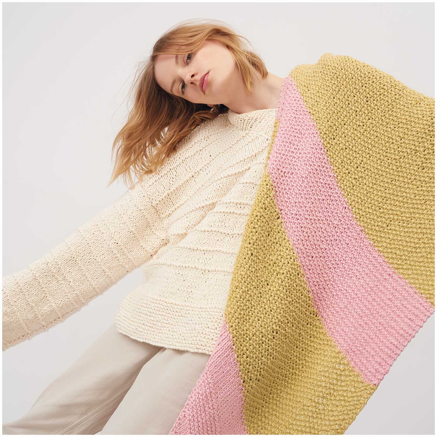 Creative So Cool + So Soft Cotton chunky: Frau trägt gestrickten Schal in Gelb und Rosa, kombiniert mit cremefarbenem Pullover.