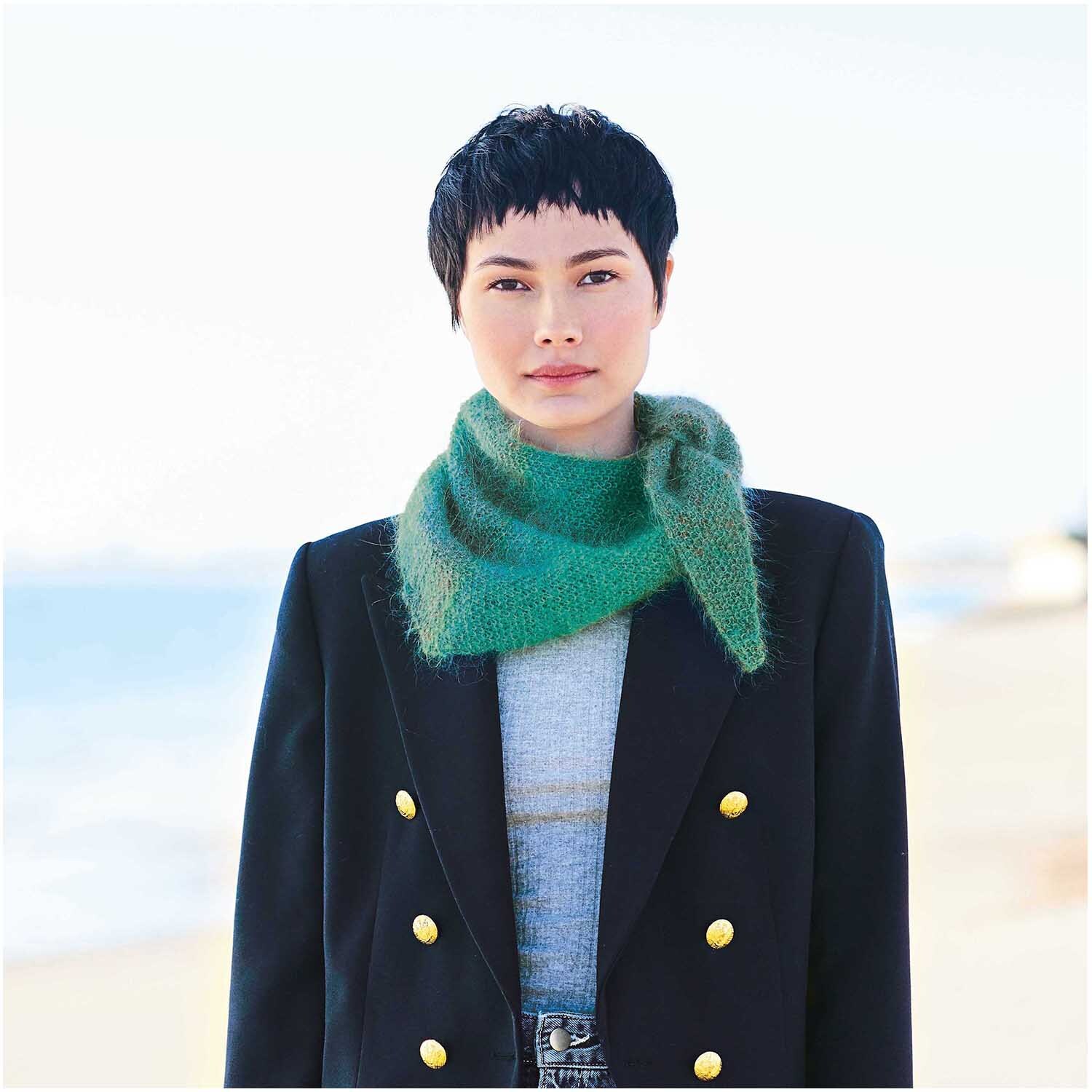 Fashion Mohair Rainbows: Frau trägt einen eleganten, aquafarbenen Schal von Rico Design am Strand.