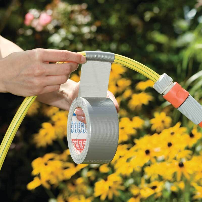 Klebeband extra Power® Universal wird im Garten verwendet, um gelbe Kabel zu befestigen. Im Hintergrund sind gelbe Blumen zu sehen.