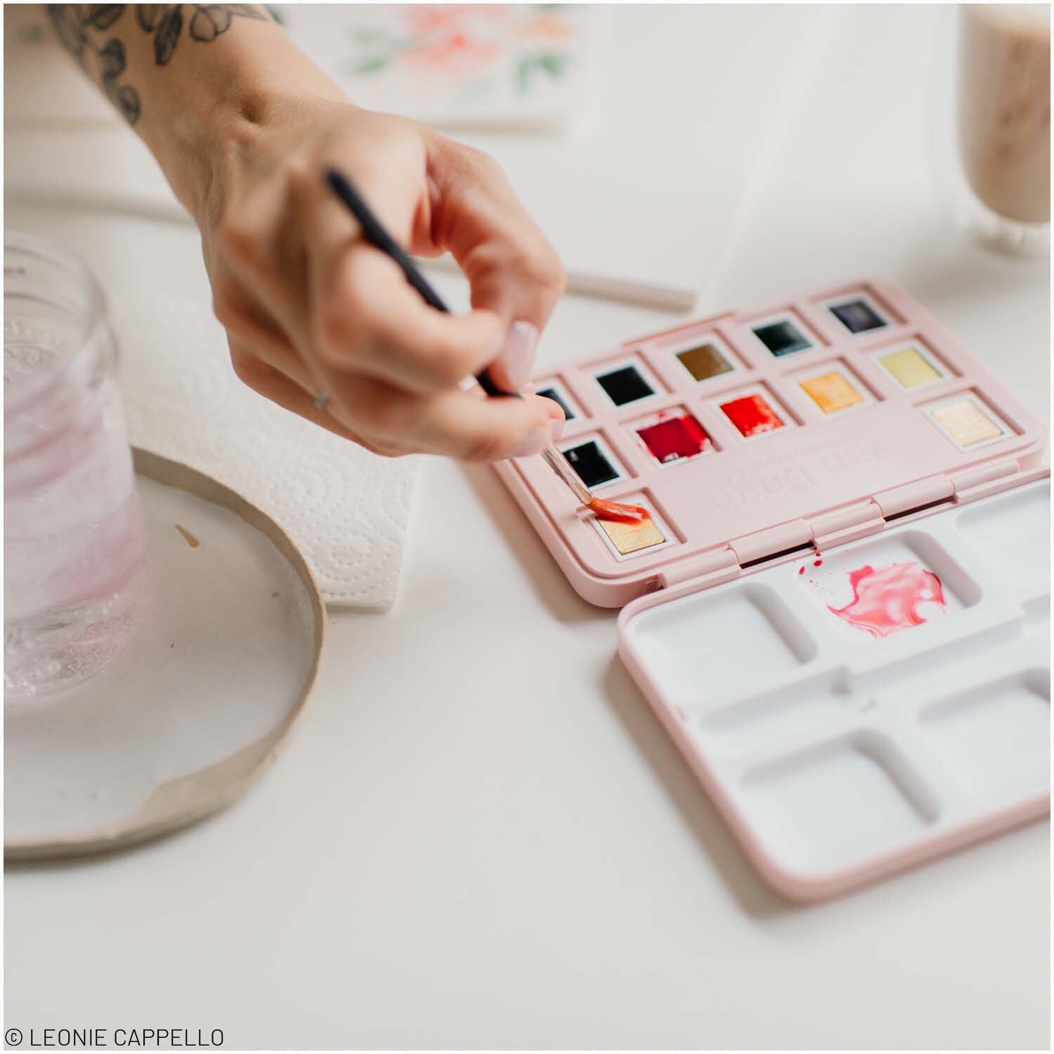 van Gogh Aquarell Set 12 Näpfchen: Eine Hand mischt Farben in einem kompakten, mehrfarbigen Malkasten. Ideal für kreative Projekte.