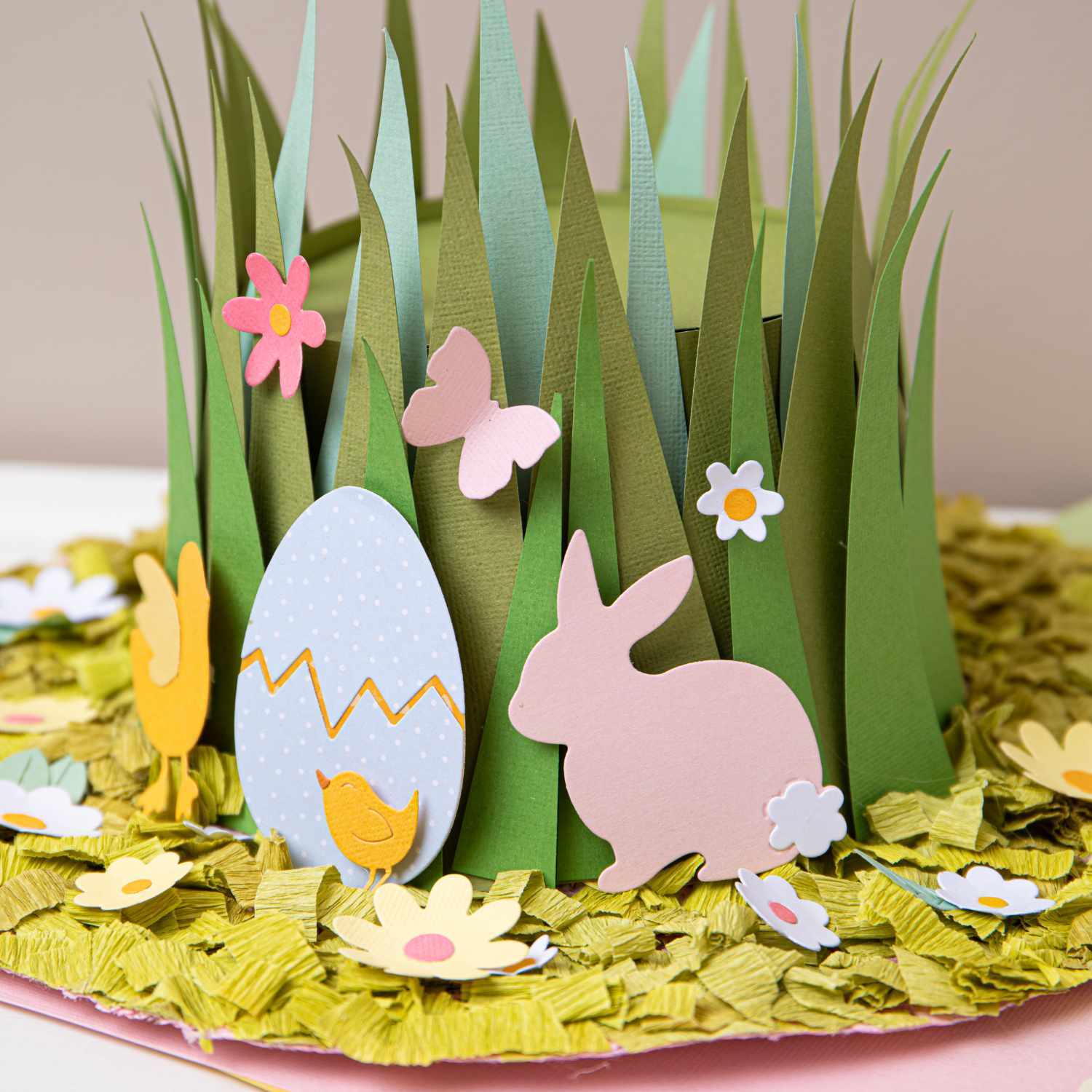 Thinlits Die Set Basic Easter Shapes zeigt bunte Osterdekoration mit Gras, Blumen, Ei und Hase. Ideal für kreative Frühlingsprojekte.