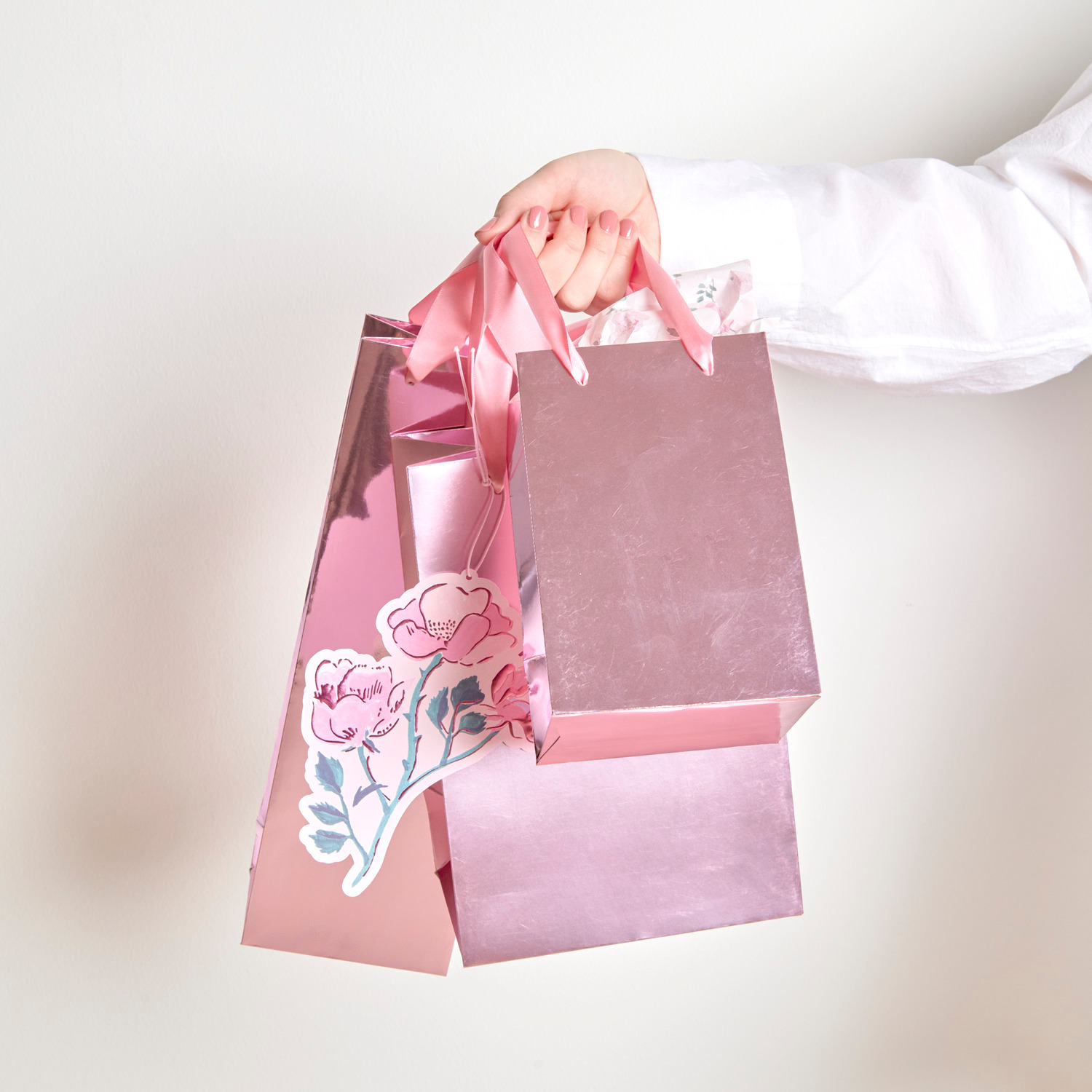 Flaschentüte Metallic Glänzend in Rosa, gehalten von einer Hand. Ideal für Geschenke.