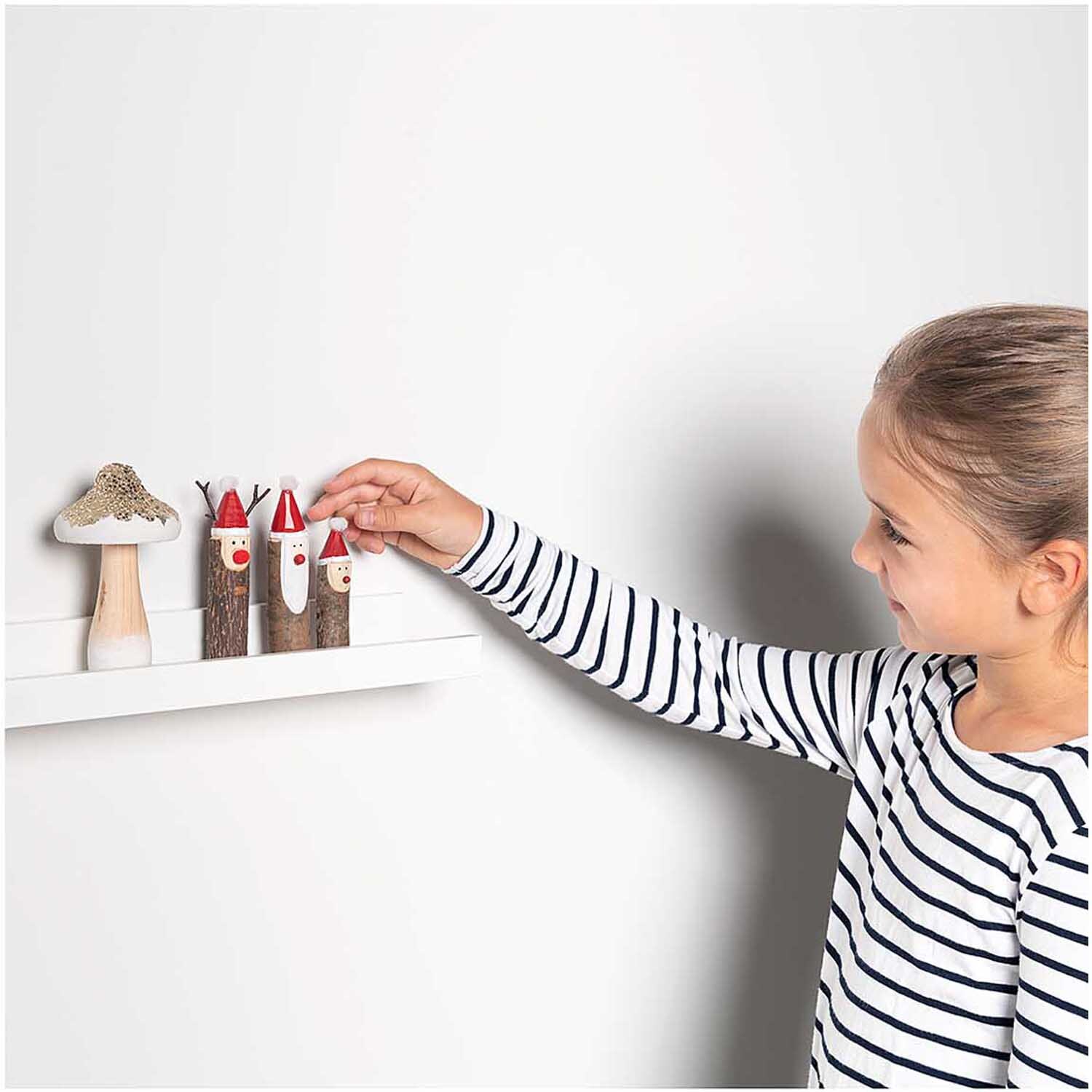Holzfigur Rentier 7x12,5cm von Rico Design: Kind dekoriert ein Regal mit bunten Holzfiguren.