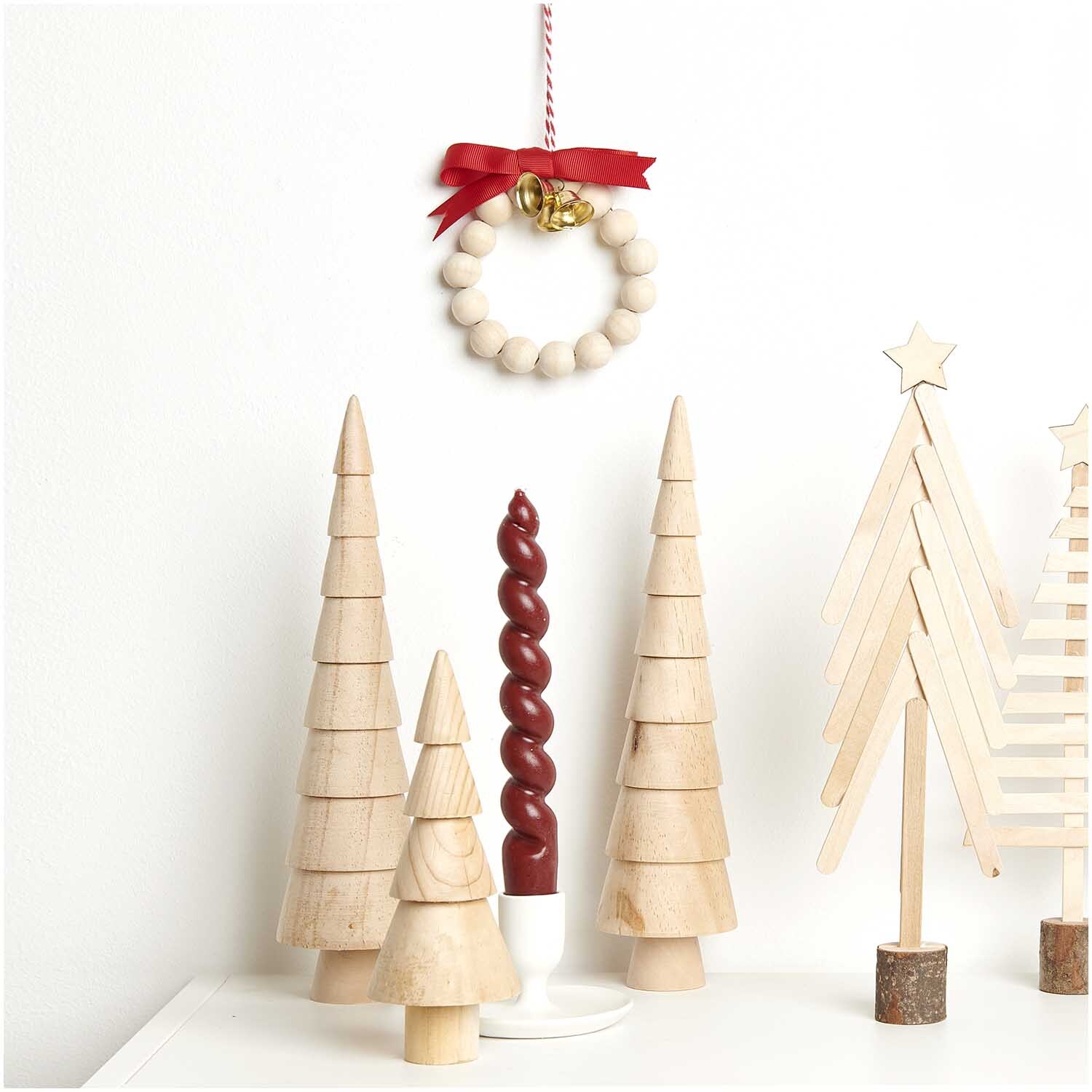 Bastelset Holzperlen Kranz natur: Ein dekorativer Kranz aus Holzperlen mit rotem Band, umgeben von Holz-Weihnachtsbäumen. Ideal für kreative Dekorationen.
