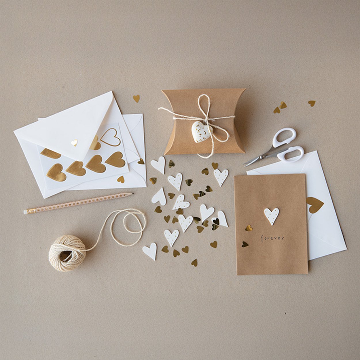 Geschenkschachteln, Karten mit Umschlag und Streuherzen, Herzsticker und Kordel in weiß, braun und goldenen Farben. Flatlay von Produkten. 
