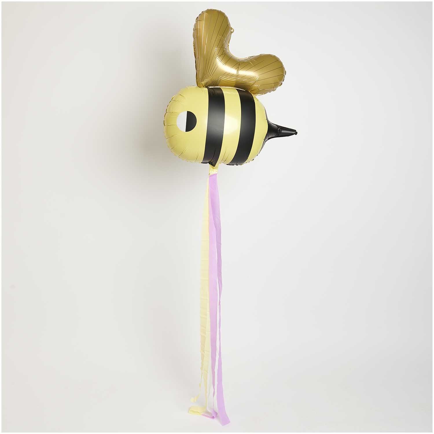 Folienballon Biene 60x70cm von Rico Design in Gelb und Schwarz mit Herzflügeln und bunten Bändern.