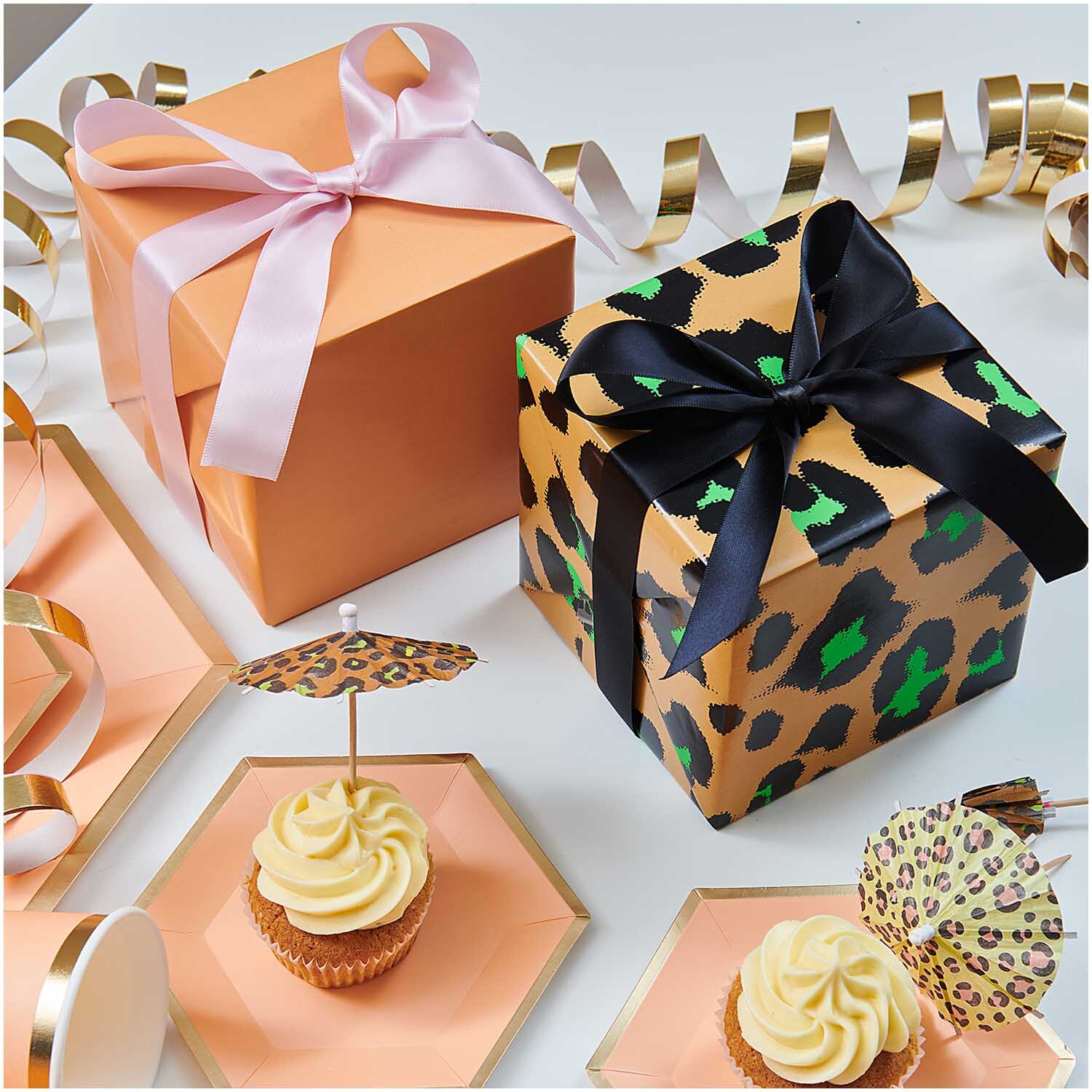Paper Poetry Geschenkpapier zeigt honigfarbene Schachteln mit Schleifen, umgeben von Cupcakes und Dekorationen.