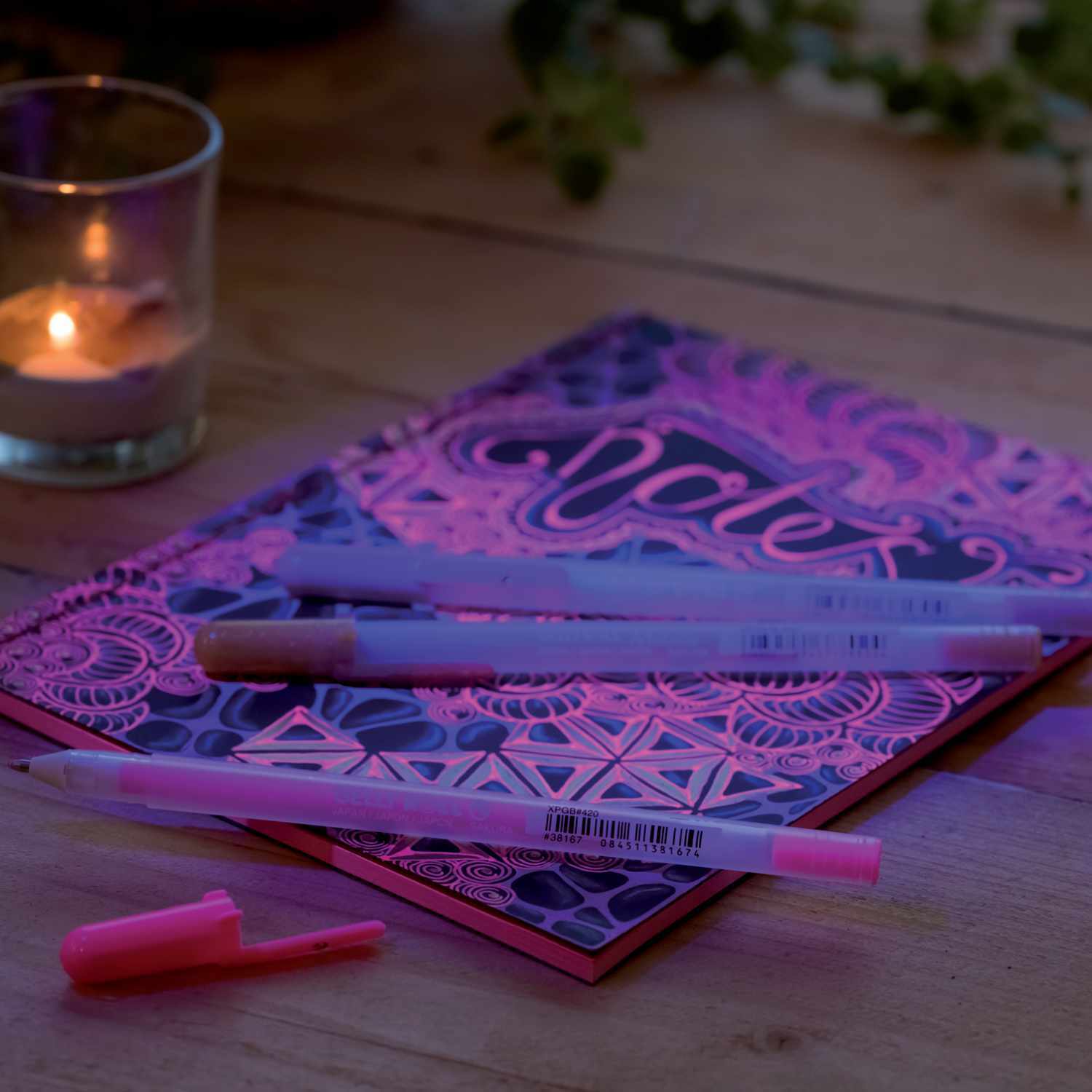 Gelly Roll Moonlight Gelstift auf einem kunstvoll gestalteten Notizbuch, umgeben von Kerzenlicht.