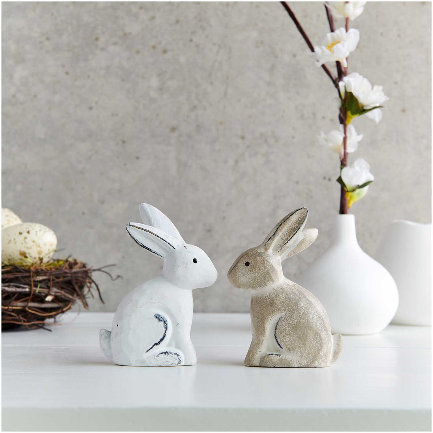 Holzanhänger Hase groß weiß 1 Stück: Zwei dekorative Hasenfiguren auf weißem Tisch, umgeben von Frühlingsdeko.