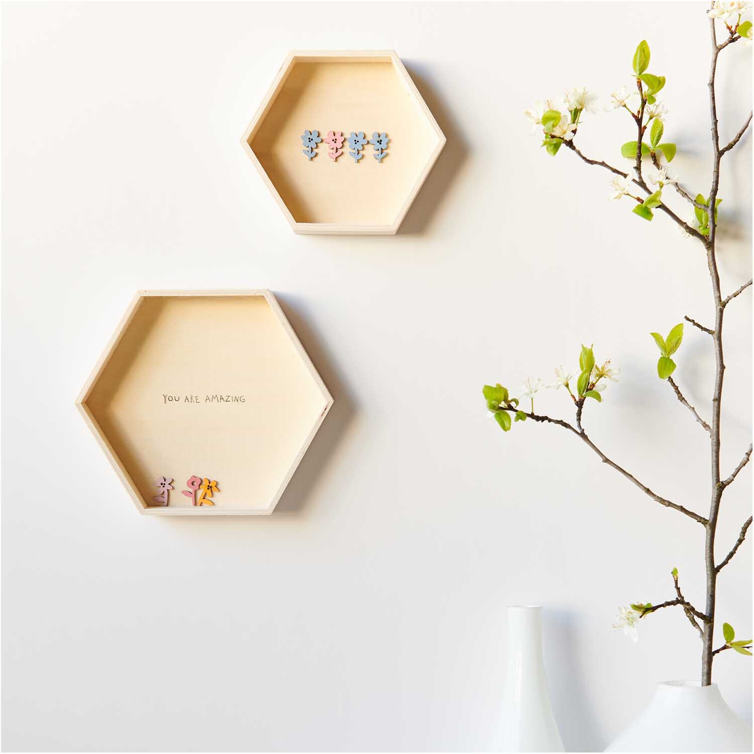 Holzstreu Blume 48 Stück: Zwei sechseckige Holzrahmen mit bunten Blumenmotiven an einer weißen Wand.