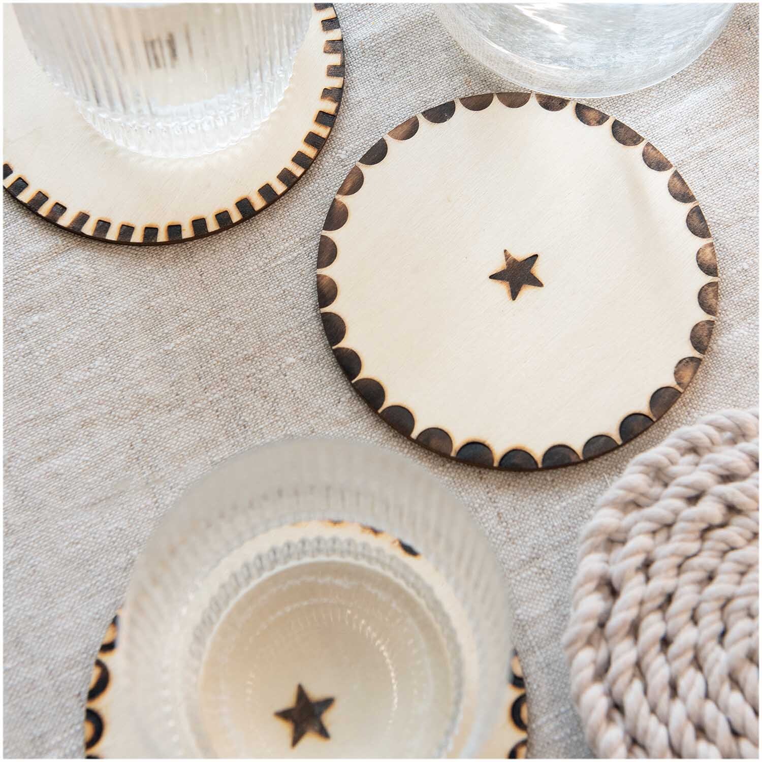 Brennstempel-Set für Brandmalkolben von Rico Design, 5-teilig. Abgebildet sind Holzuntersetzer mit Sternmotiv auf einem Tisch.
