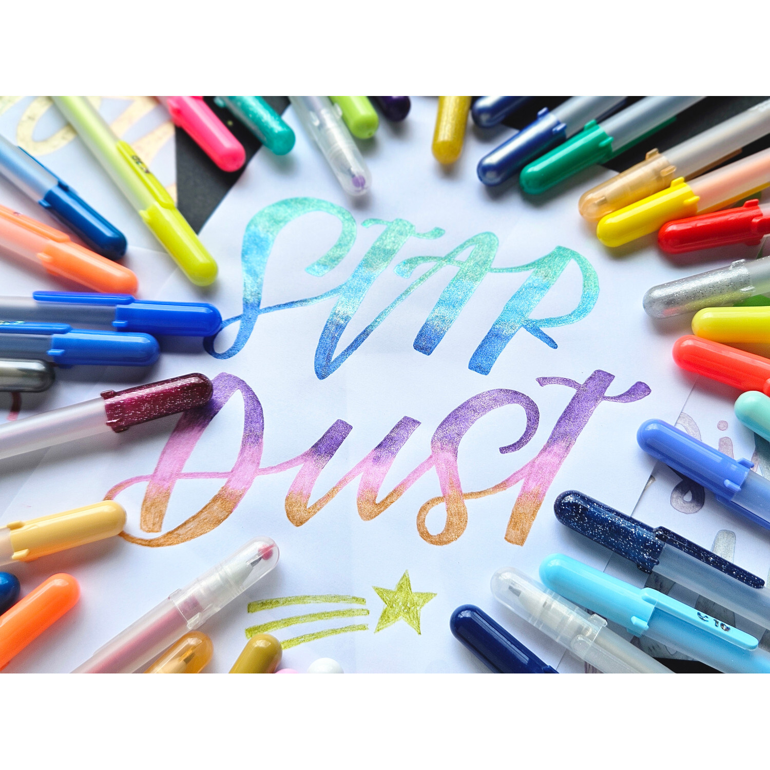 Gelly Roll Stardust Glitter Gelstifte Set 12 Stück in bunten Farben, arrangiert um den Schriftzug "Star Dust". Ideal für kreative Projekte.