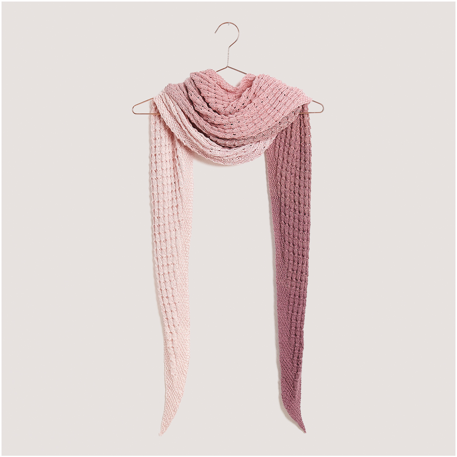 Strickset Dreieckstuch Modell 18 aus Lovewool Nr. 18, in Rosa- und Pinktönen, auf einem Kleiderbügel präsentiert.