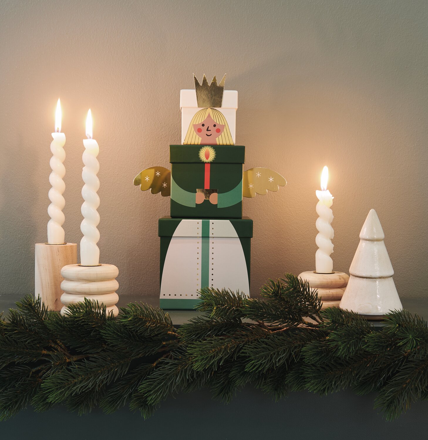 Geschenkboxen-Set Engel: Dekoratives 6-teiliges Set mit grünen und goldenen Details, umgeben von Kerzen und Tannenzweigen.