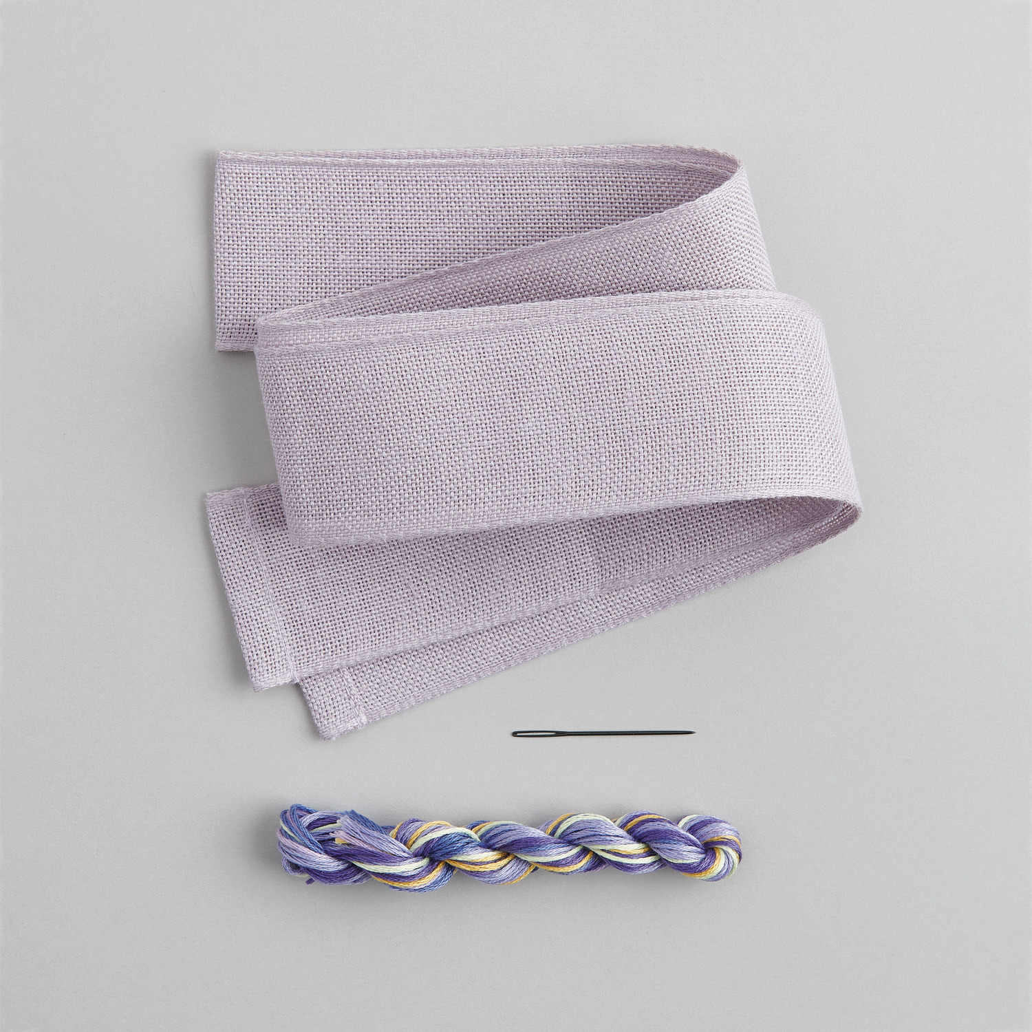 Stickpackung Schleife Vergissmeinnicht von Rico Design zeigt eine lila Schleife mit Nadel und Garn.